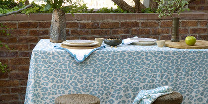Blue Iconic Leopard print tablecloth set on an outdoor table against a brick wall.