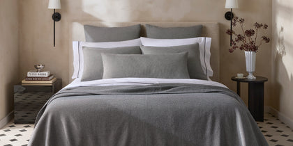 Gray Jackson houndstooth-textured bedding, styled on a bed with a tan upholstered headboard.