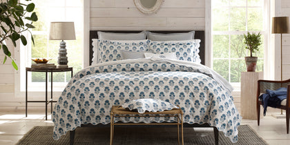 Blue Joplin floral print bedding with scalloped edges, styled on a dark wood bed.