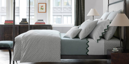Green Laksha medallion print bedding with a scalloped trim, styled on a four-poster bed.