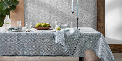 Blue Laksha medallion print tablecloth set with candles and a bowl of green hydrangea.