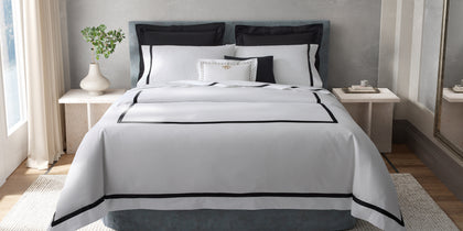 White Lowell bedding with black bordered trim, styled on a bed with black euro pillows.