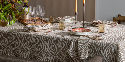 Taupe zebra-print Regine tablecloth set with candles, glassware, and place settings.