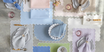 Scalloped-edge Savannah Gardens placemats and napkins in pastel colors arranged with place settings.