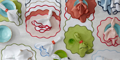 Scallop Edge placemats and napkins in assorted wavy-trimmed colors arranged with colorful plates.