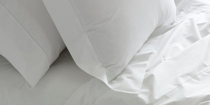 White Sierra Hemstitch pillows and rumpled sheets on a bed.