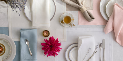 Valentina Hemstitch placemats and napkins in assorted pastel colors arranged with place settings and a dahlia.