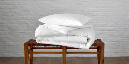 Valletto white down pillow and comforter on a woven leather bench
