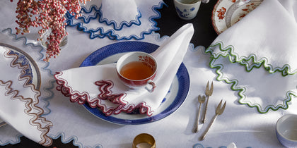 White Wave placemats and napkins with wavy trim in assorted colors set with blue and white china and teacups.