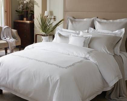 A plush bed made with fine linens and embroidered shams. 